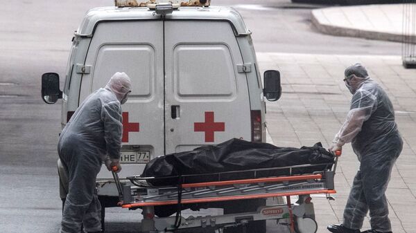 Медицинские работники перевозят тело умершего на территории карантинного центра в Коммунарке