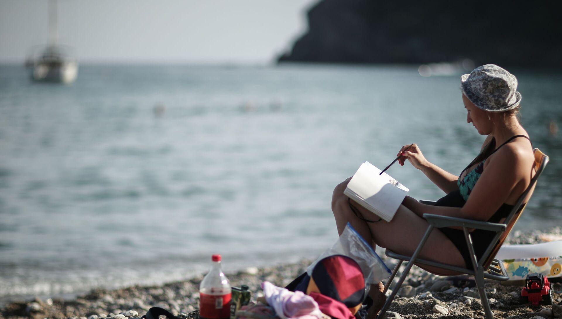 Девушка читает книгу на пляже в поселке Новый Свет в Крыму - РИА Новости, 1920, 16.05.2021