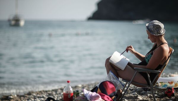 Девушка читает книгу на пляже в поселке Новый Свет в Крыму