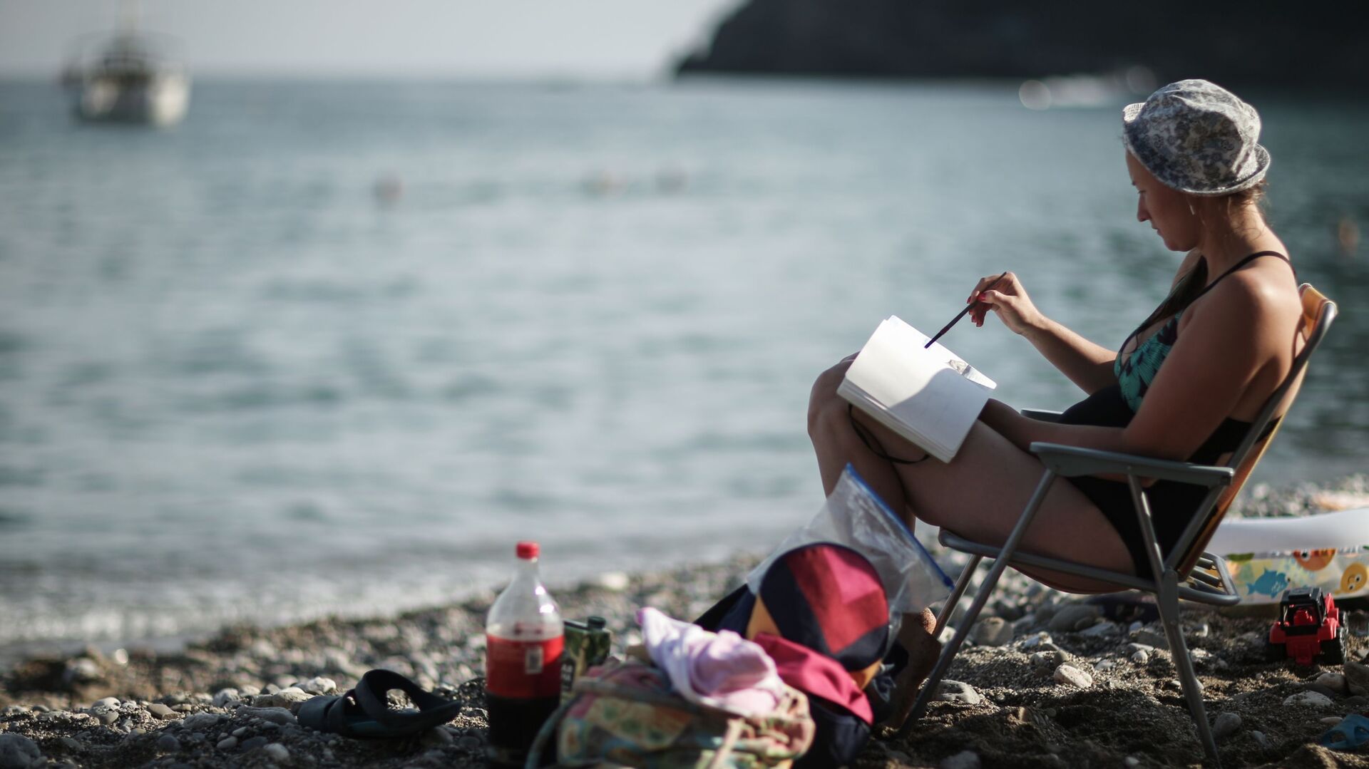 Девушка читает книгу на пляже в поселке Новый Свет в Крыму - РИА Новости, 1920, 16.05.2021