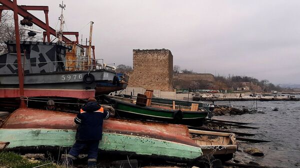 Рыбацкие лодки-фелюги на фоне Доковой башни XIV века и бетонного пирса. Феодосия