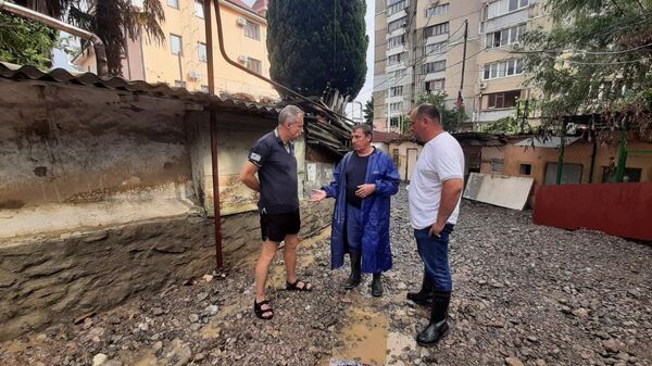 Крымский премьер Юрий Гоцанюк (в центре) и министр ЖКХ РК Сергей Донец объясняют местному жителю порядок компенсаций после наводнения. Ялта, 26 июня 2021 года