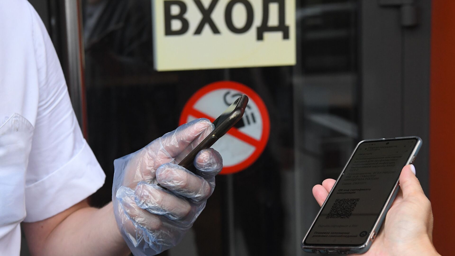 Посетитель показывает специальный QR-код на экране смартфона на входе в кафе - РИА Новости, 1920, 21.10.2021