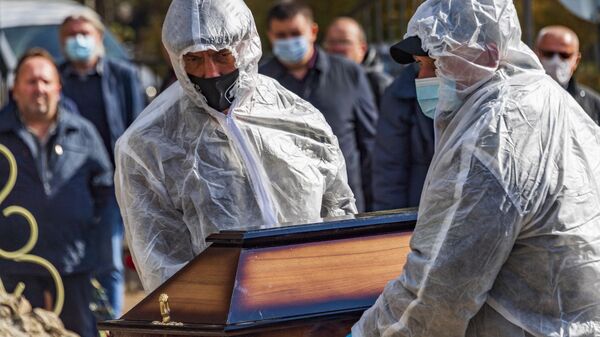 Сотрудники ГУП Ритуал несут гроб с телом умершего от коронавируса на кладбище Абдал в Симферополе