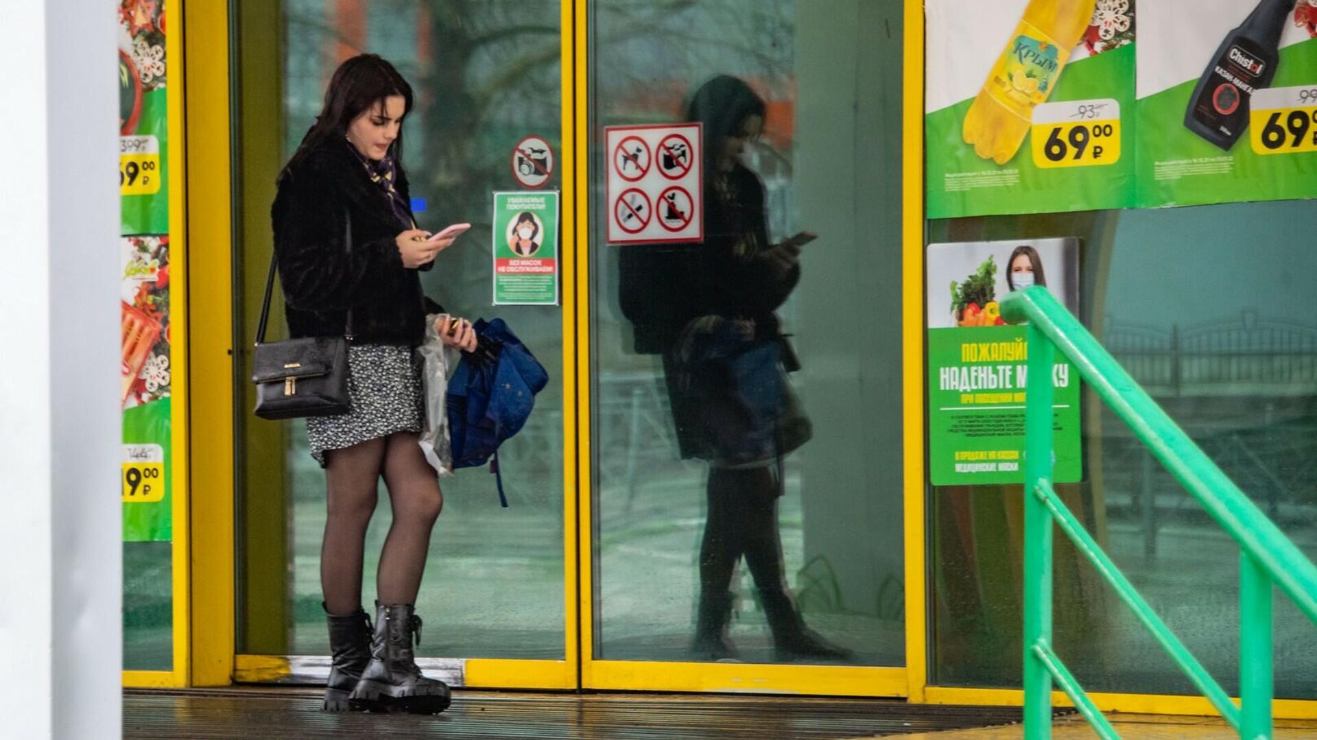 Девушка со смартфоном возле дверей торгового центра - РИА Новости, 1920, 08.02.2024