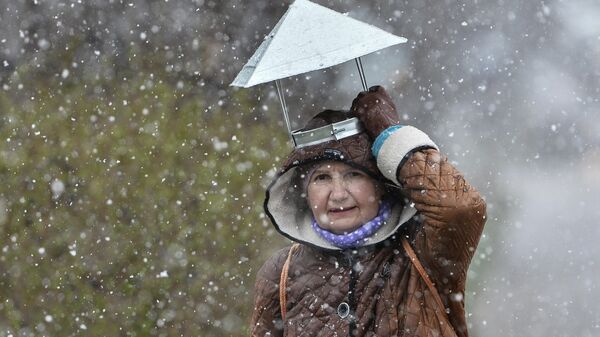 Пожилая женщина во время апрельского снегопада в Симферополе.