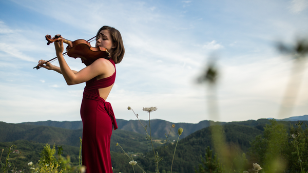 Девушка играет на скрипке в цветущих садах Крыма