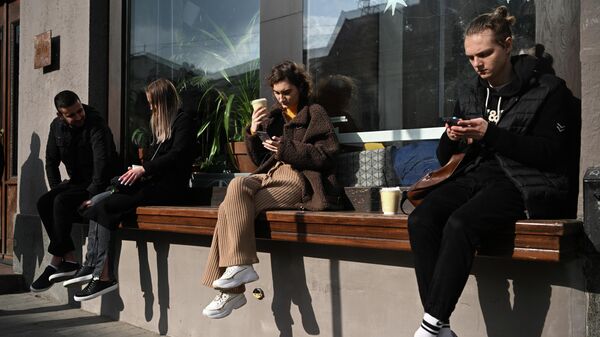 Люди на лавке у одного из кафе в Москве.