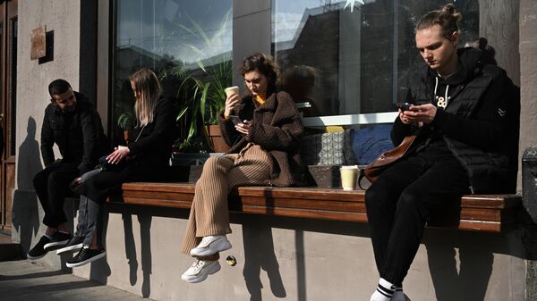 Люди на лавке у одного из кафе в Москве.