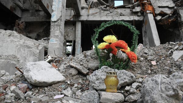 Венок и лампада на месте разрушенного здания в Мариуполе.