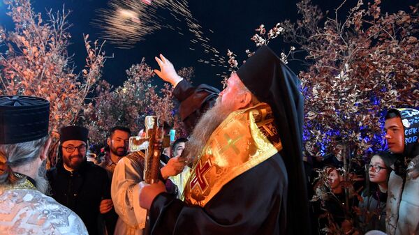 Епископ Сербской православной церкви Иоанникий на зажжении костре из сушеных дубовых ветвей в канун православного Рождества перед собором Сербской православной церкви в Подгорице