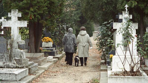 Потомки русских эмигрантов во Франции идут по аллее русского кладбища в Сент-Женевьев-де Буа.