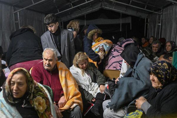 Эвакуированные люди пострадавшего в результате землетрясения турецкого города Хатай 