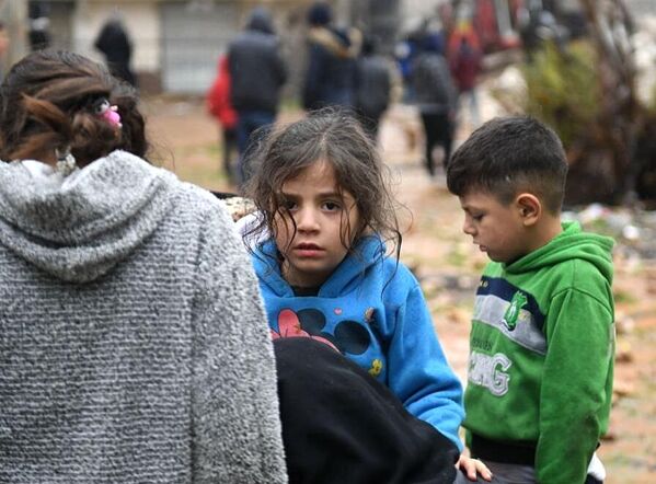 Дети у разрушенного в результате землетрясения жилого дома в сирийском Алеппо