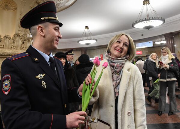Сотрудник УВД на Московском метрополитене поздравляет женщину с наступающим 8 марта 