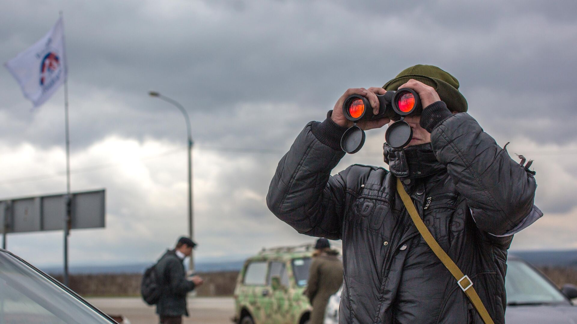 Местный житель наблюдает в бинколь за военным блокпостом на въезде в аэропорт Бельбек рядом с Севастополем - РИА Новости, 1920, 12.03.2023