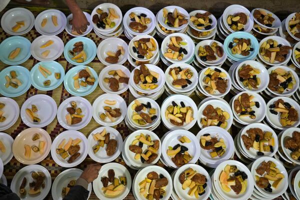Волонтеры готовят тарелки с едой для раздачи людям во время поста во время священного для мусульман месяца Рамадан в мечети в Равалпинди, Пакистан