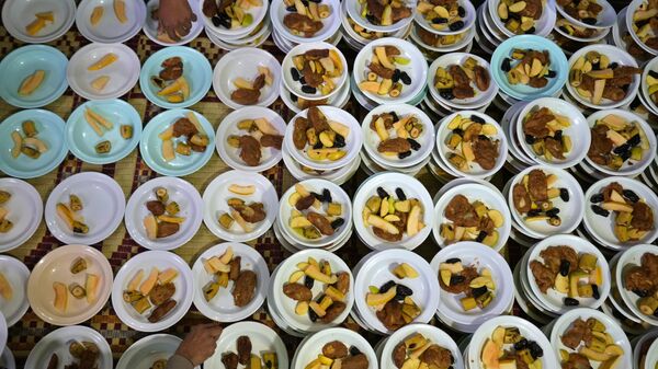 Волонтеры готовят тарелки с едой для раздачи людям во время поста во время священного для мусульман месяца Рамадан в мечети в Равалпинди, Пакистан