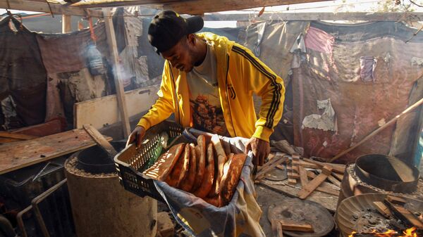 Мужчина несет свежеиспеченный хлеб тандури для продажи в лагере для перемещенных лиц из Таверги во время священного для мусульман месяца Рамадан в восточном ливийском городе Бенгази