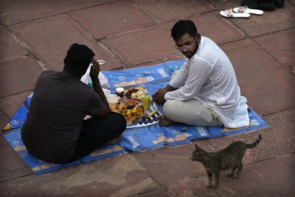 Мужчина принимают пищу в первый день священного месяца Рамадан в Джама Масджид в Нью-Дели, Индия