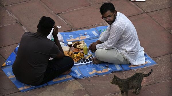 Мужчина принимают пищу в первый день священного месяца Рамадан в Джама Масджид в Нью-Дели, Индия