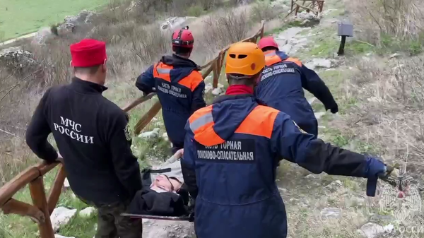 Спасатели транспортируют к скорой мужчину, упавшего с 8-метровой скалы в Бахчисарайском районе Крыма