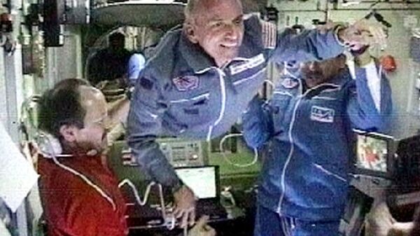 Командир космической станции Юрий Усачев и космонавт Талгат Мусабаев приветствуют калифорнийского миллионера Денниса Тито на международной космической станции, 2001 год