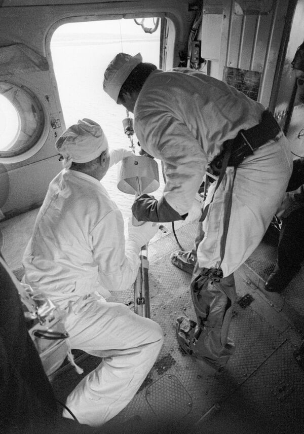 Специалисты с борта вертолета берут пробы воды в охладителях реактора Чернобыльской АЭС после катастрофы