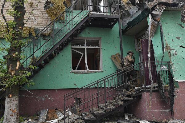 Боец ЧВК Вагнер заходит в разрушенный дом в Артемовске