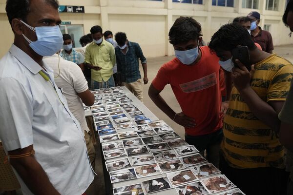 Люди смотрят на фотографии неопознанных жертв столкновения поездов в Индии 