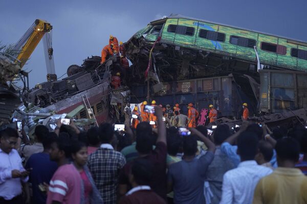 Спасатели вытаскивают тело жертвы столкновения поездов в Индии 