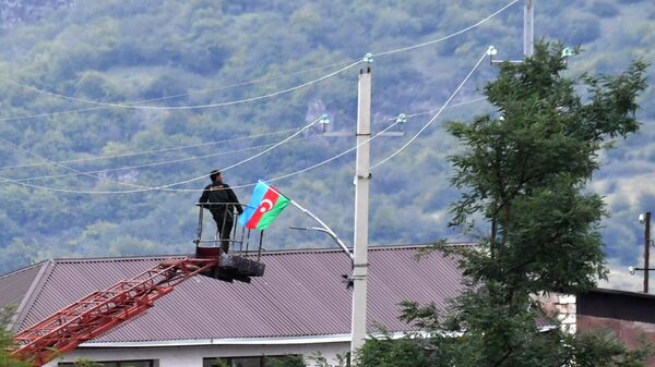 Мужчина устанавливает флаг Азербайджана в одном из населенных пунктов Нагорного Карабаха.