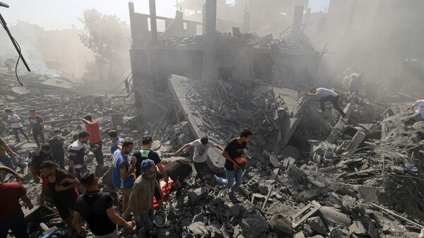 Люди ищут выживших среди обломков зданий, разрушенных во время бомбардировки на юге сектора Газа