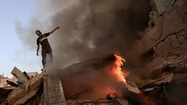 Палестинец на обломках рухнувшего здания в секторе Газа 4 ноября 2023 года