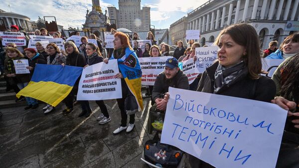 Родственники украинских военнослужащих держат плакаты с требованием их демобилизации