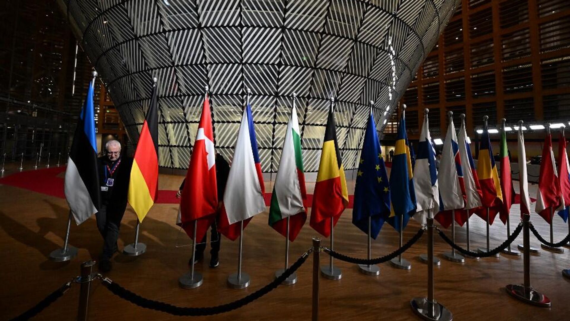 Рабочий вывешивает флаги европейских стран перед прибытием европейских лидеров на саммит ЕС-Западные Балканы в европейской штаб-квартире в Брюсселе - РИА Новости, 1920, 14.12.2023