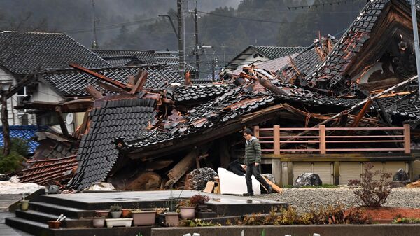 Мужчина проходит мимо обрушившегося дома в городе Анамидзу, префектура Исикава, 3 января 2024 года