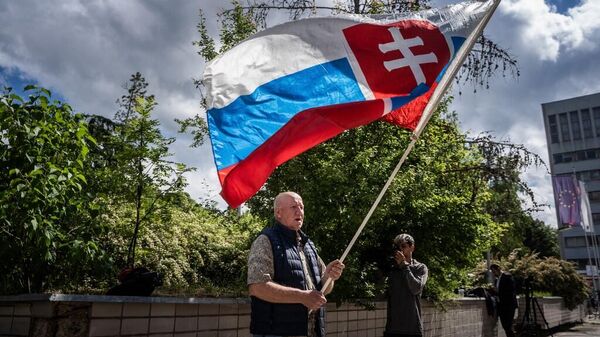 Мужчина с флагом Словакии, который пришел к больнице, где лечится премьер-министр Словакии Роберт Фицо