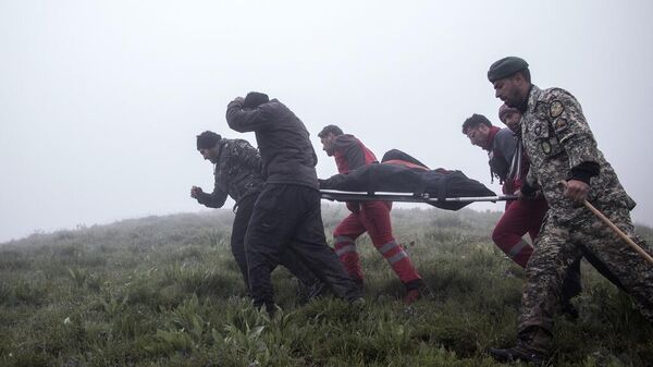 Члены спасательной команды несут жертву после крушения вертолета с президентом Ирана Эбрагимом Раиси