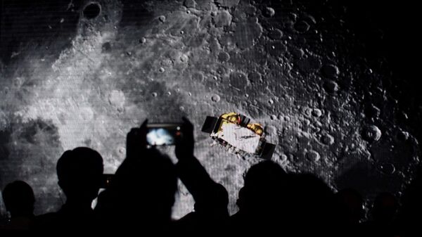 Зрители фотографируют экран, демонстрирующий видео о китайском лунном зонде Чанъэ-5
