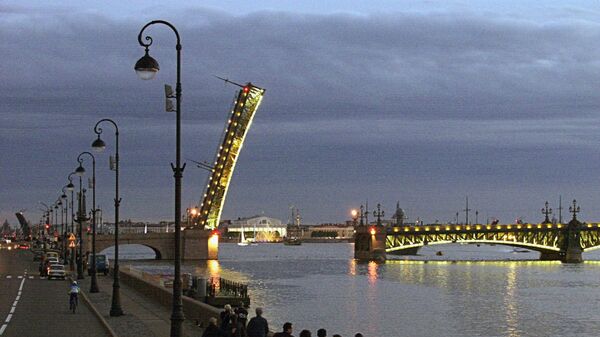 Жители и гости Санкт-Петербурга во время ночной прогулки по набережной наблюдают, как разводится Троицкий мост