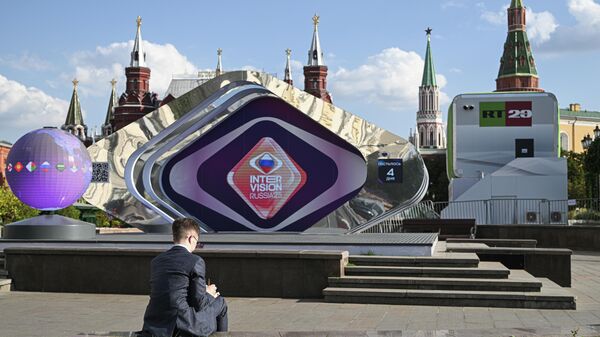 Мужчина перед с ценой с символикой международного музыкального конкурса Интервидение на Манежной площади в Москве.