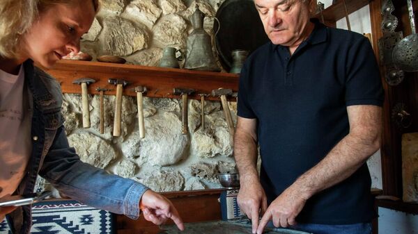 Медник Рустем Дервиш рассказывает корреспонденту РИА Новости Крым о символах чеканки на старинном подносе