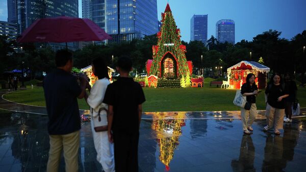 Люди проходят мимо рождественской елки, установленной в парке в Джакарте, Индонезия Люди проходят мимо рождественской елки, установленной в парке в Джакарте, Индонезия