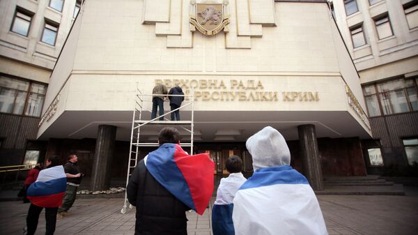 Рабочие снимают вывеску Верховной Рады Автономной республики Крым на украинском языке.