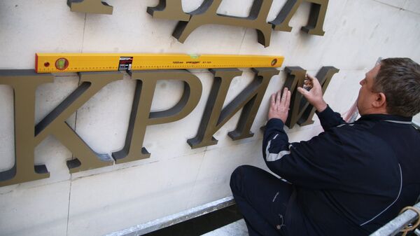 Рабочий крепит на фасад Государственного совета Республики Крым название парламента на украинском языке. Архивное фото