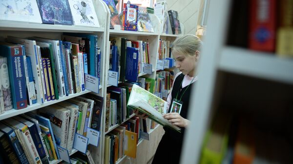 Девочка читает книгу в библиотеке