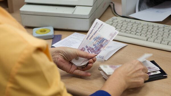 Сотрудница одного из московских отделений Почты России выдает ежемесячное денежное пособие