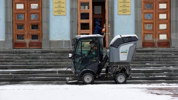 Машина убирает снег на входе в здание Совета министров Крыма