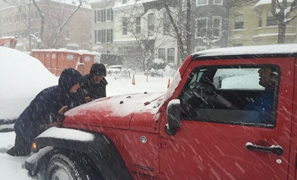 Люди толкают автомобиль, застрявший в снегу